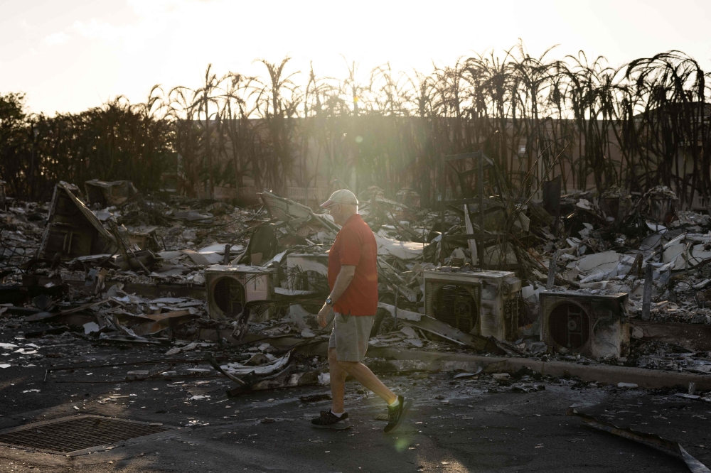 A resident looks around a charred apartment complex in the aftermath of a wildfire in Lahaina, western Maui, Hawaii on August 12, 2023. (Photo by Yuki Iwamura / AFP)