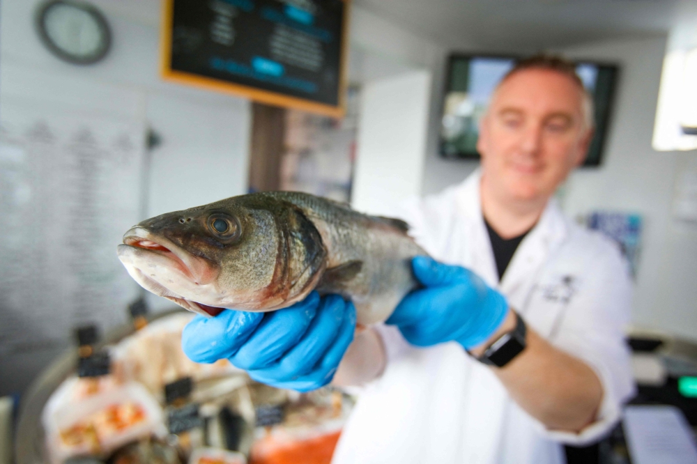 Fishmonger Michael O'Donnell poses for a photograph with some of his fish stock in Killybegs, western Ireland on August 4, 2023. (Photo by Paul Faith / AFP