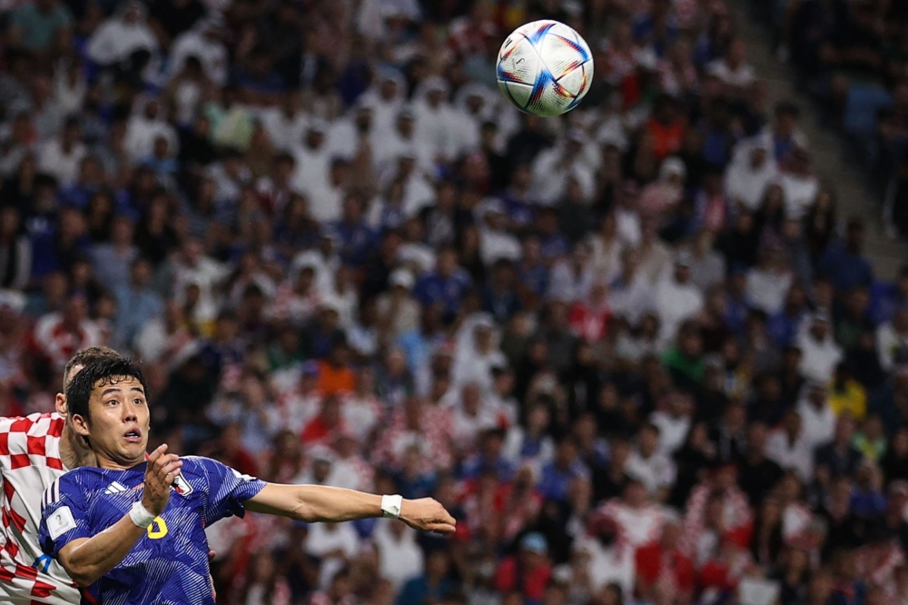 Japan's midfielder Wataru Endo jumps to head the ball during the Qatar 2022 World Cup round of 16 football match between Japan and Croatia at the Al Janoub Stadium in Al Wakrah, south of Doha on December 5, 2022.  (Photo by Adrian Dennis / AFP)