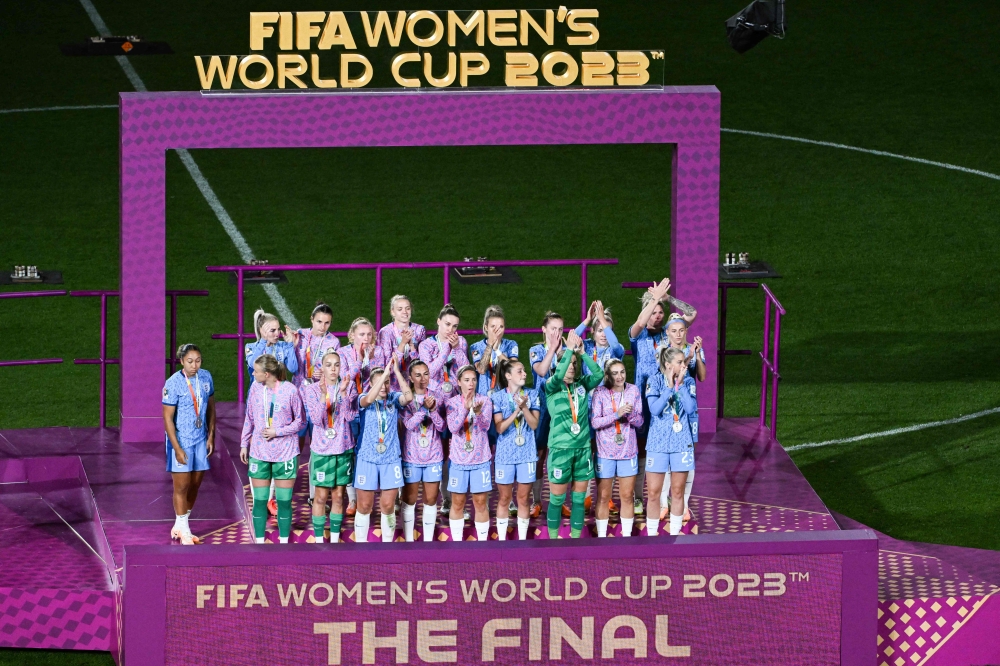 England's players stand on the podium after receiving the runners up medals after the Australia and New Zealand 2023 Women's World Cup final football match between Spain and England at Stadium Australia in Sydney on August 20, 2023. (Photo by Saeed KHAN / AFP)