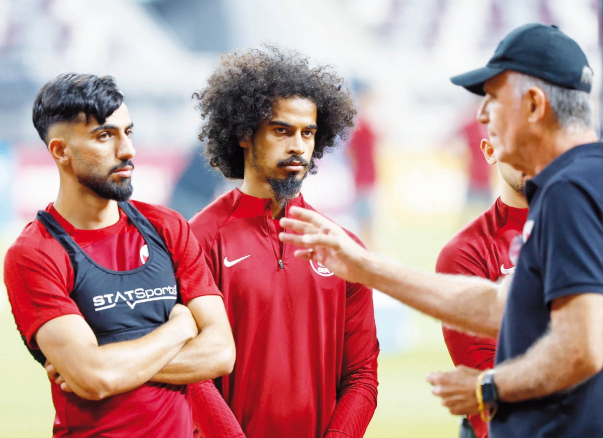 Qatar coach Carlos Queiroz (right) speaks to Akram Afif and Tarek Salman.