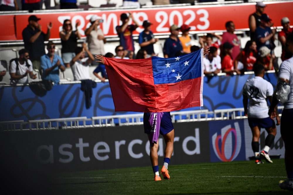 A Samoan player waves the Samoan flag after winning the France 2023 Rugby World Cup Pool D match between Samoa and Chile at Stade de Bordeaux in Bordeaux, south-western France on September 16, 2023. (Photo by Christophe ARCHAMBAULT / AFP)
