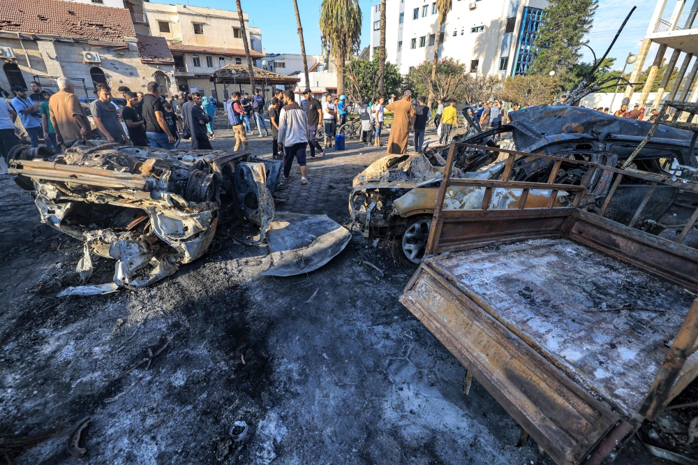 People search through debris outside the site of the Ahli Arab hospital in central Gaza on October 18, 2023 in the aftermath of an overnight blast there. (Photo by Mahmud Hams / AFP)