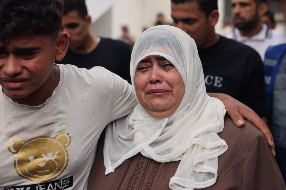 A woman is comforted as she grieves at a hospital where the injured and dead are brought following an Israeli air strike on Rafah, the southern Gaza Strip on October 23, 2023. (Photo by Mohammed Abed / AFP)