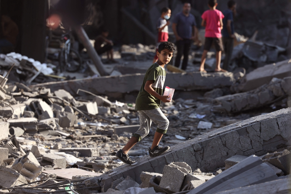 Palestinians walk on the rubble of buildings destroyed by Israeli bombardment in the Nuseirat refugee camp, in the central Gaza Strip on October 30, 2023, amid the ongoing battles between Israel and Hamas. Photo by MOHAMMED ABED / AFP