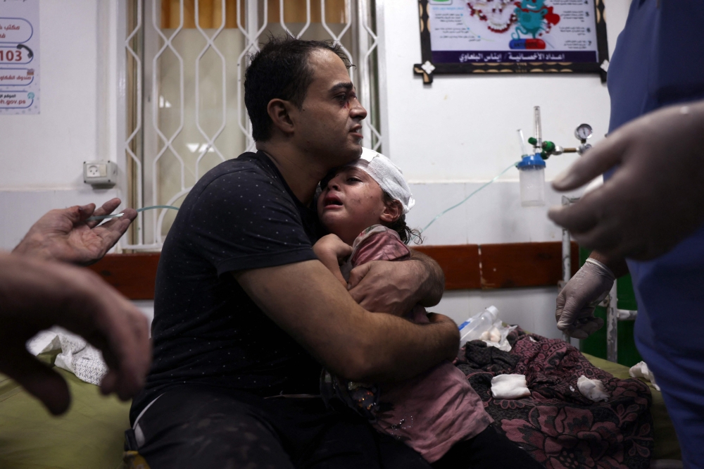 Palestinian man cradles an injured child at the Najjar hospital following an Israeli air strike on a home in Rafah on October 30, 2023. Photo by Said KH / AFP