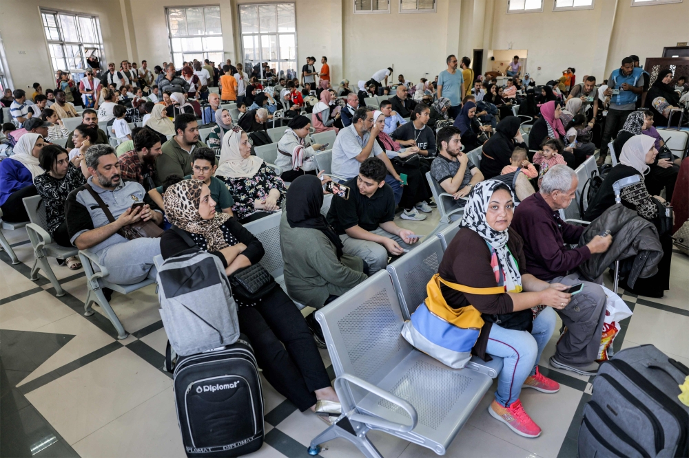 People sit in the waiting area at the Rafah border crossing in the southern Gaza Strip before crossing into Egypt on November 1, 2023. Photo by MOHAMMED ABED / AFP