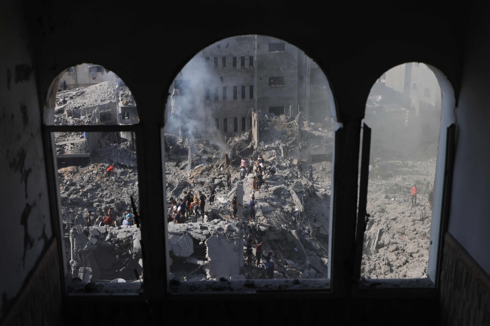 People sift through the smouldering rubble of buildings destroyed in an Israeli strike on the Bureij refugee camp in the central Gaza Strip on November 2, 2023. (Photo by Mahmud Hams / AFP)