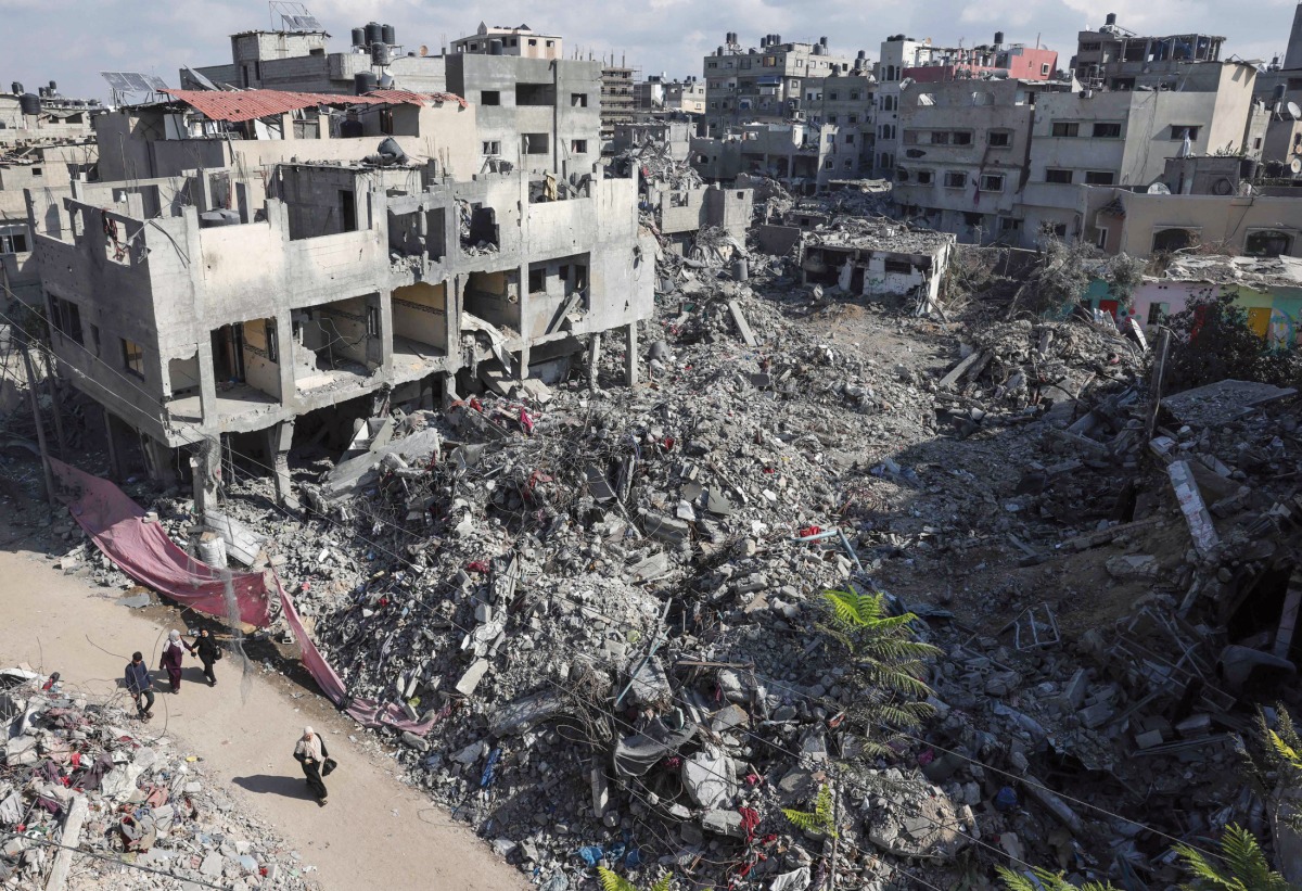 People walk past buildings destroyed in the Israeli bombardment in Bureij, central Gaza Strip, yesterday.