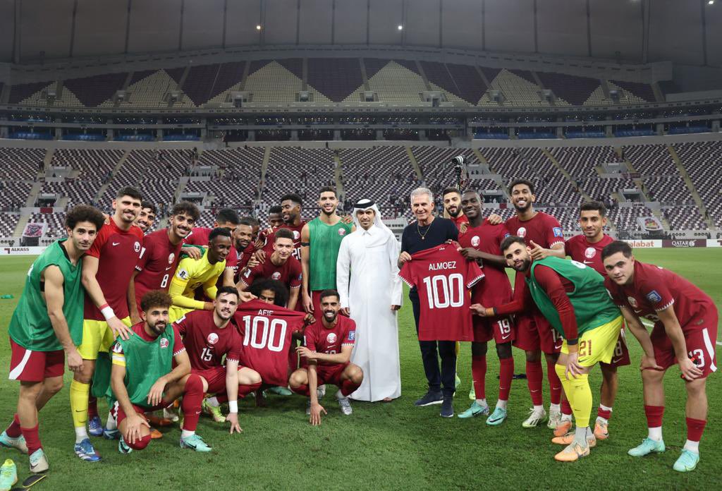 Qatar strikers Almoez Ali (right) and Akram Afif holding jerseys to mark their 100th international-match milestones along with  Qatar Football Association President Jassim Rashid Al Buenain and Qatar head coach Carlos Queiroz besides teammates.