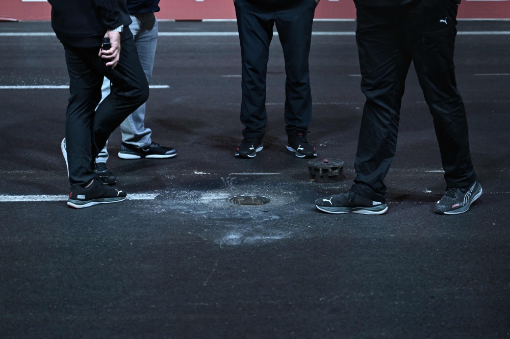 Race Operations officials inspect a loose drain cover on the track during the first practice session for the Las Vegas Formula One Grand Prix on November 16, 2023, in Las Vegas, Nevada. Photo by Jim WATSON / AFP