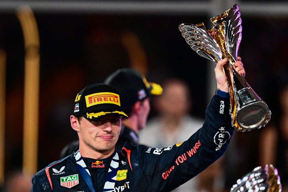 Red Bull Racing's Dutch driver Max Verstappen celebrates on the podium with the trophy after winning the Abu Dhabi Formula One Grand Prix at the Yas Marina Circuit in the Emirati city on November 26, 2023. (Photo by Jewel SAMAD / AFP)
