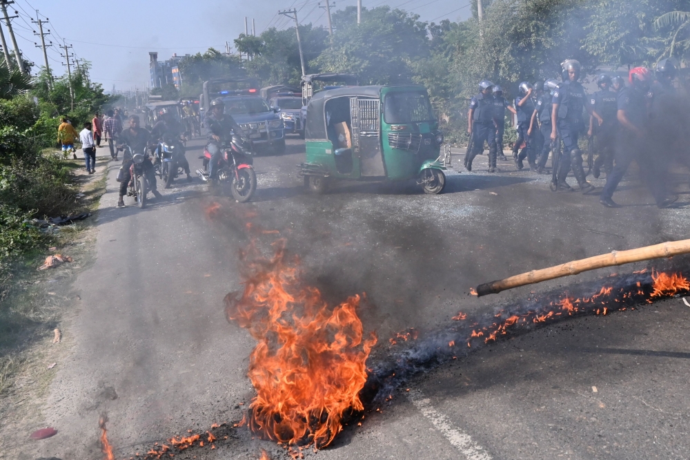 Motorists watch as Bangladesh Nationalist Party (BNP) activists set fire on a road during clashes with the police in Araihazar, on October 31, 2023. (Photo by Munir Uz Zaman / AFP)

