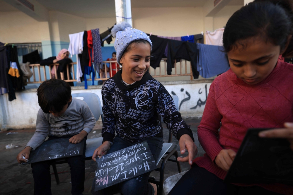 Displaced Palestinian children gather in the courtyard of the Taha Hussein school which is used as a temporary shelter in Rafah in the southern Gaza Strip on November 29, 2023. (Photo by Mahmud Hams / AFP)