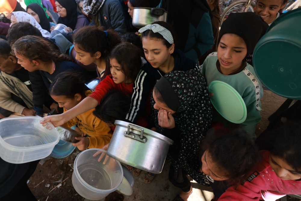 Displaced Palestinian children queue for food and bread donations in the southern Gaza Strip city of Rafah, on November 30, 2023. Photo by MOHAMMED ABED / AFP