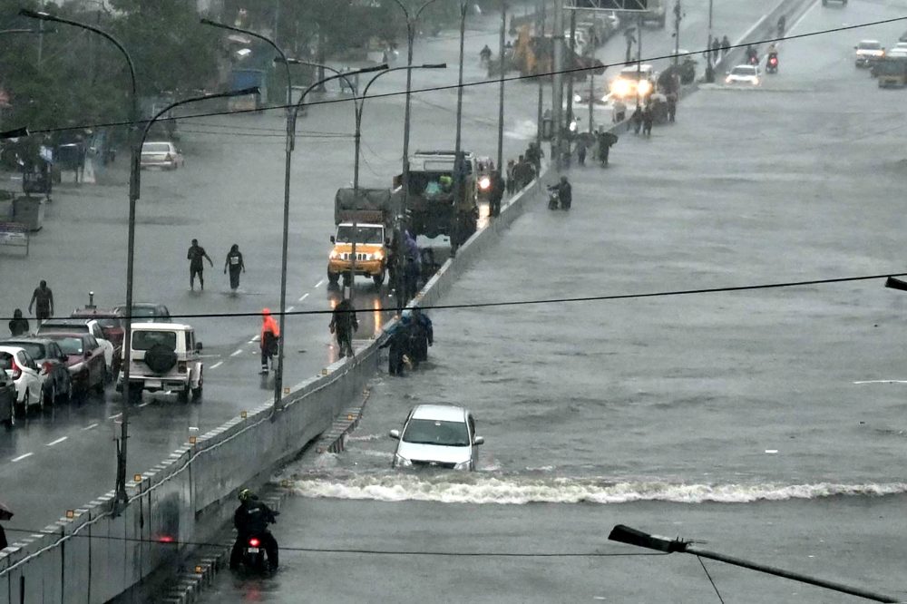 Commuters make their way through a flooded road after heavy rains in Chennai on December 4, 2023. (All photos by R Satish Babu/ AFP)