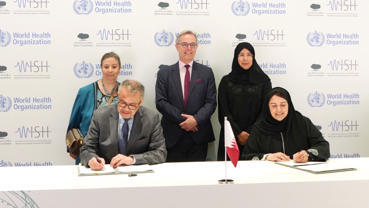 Minister of Public Health H E Dr. Hanan Mohamed Al Kuwari looks on as WHO chief Dr. Tedros Adhanom Ghebreyesus (left) and WISH CEO Sultana Afdhal sign the document.