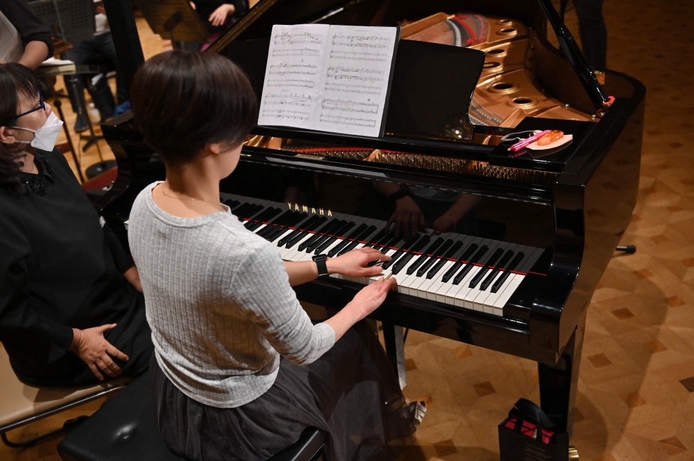 This picture taken on December 20, 2023 shows Hiroko Higashino (C) playing an AI-powered piano during a Christmas concert rehearsal of Beethoven Symphony No 9 with the Yokohama Sinfonietta orchestra in Tokyo. (Photo by Kazuhiro Nogi / AFP)
 