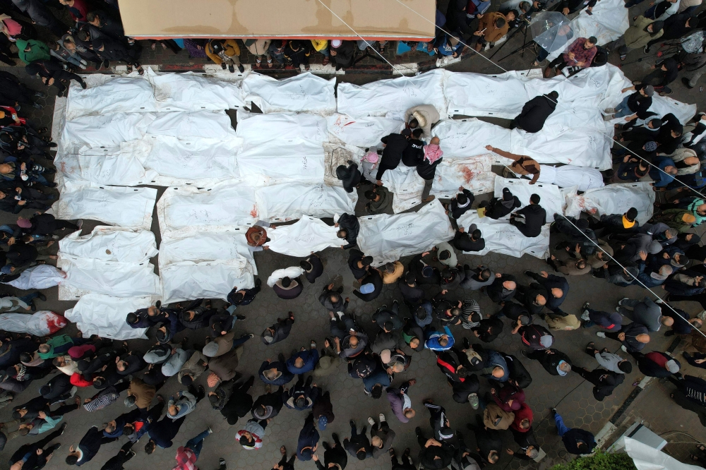 An aerial view shows Palestinians mourning their relatives, killed in an overnight Israeli strike on the Al-Maghazi refugee camp, during a mass funeral at the Al-Aqsa hospital in Deir Al-Balah, in the southern Gaza Strip, on December 25, 2023. Photo by MAHMUD HAMS / AFP