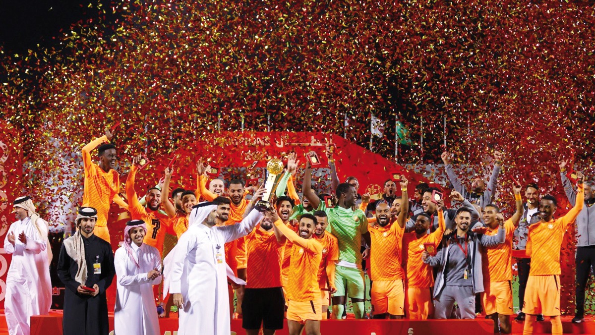 Umm Salal players and officials celebrate with the trophy.