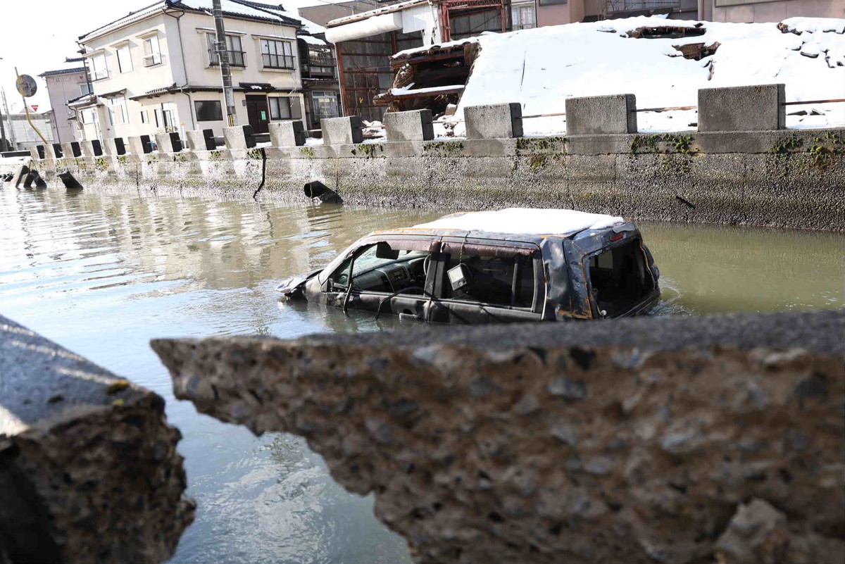 A vehicle believed to be washed away by the tsunami sits in water next to damaged buildings in the disaster-hit city of Noto, Ishikawa prefecture on January 9, 2024, after a major 7.5 magnitude earthquake struck the Noto region in Ishikawa prefecture on New Year's Day. Photo by JIJI PRESS / AFP