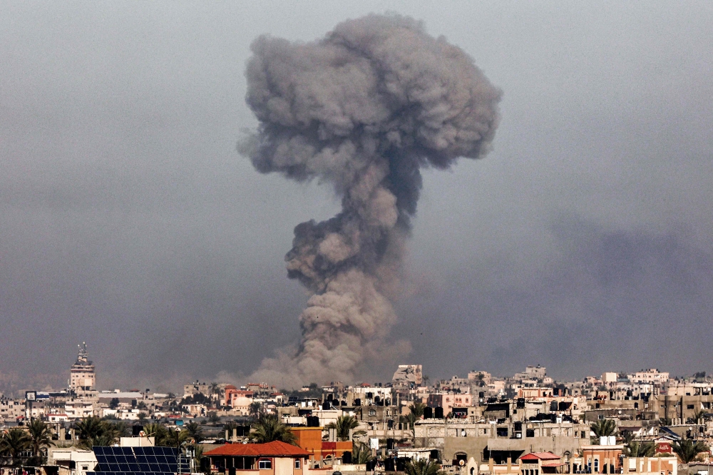 A smoke plume erupts over Khan Yunis from Rafah in the southern Gaza strip during Israeli bombardment on January 8, 2024. (Photo by AFP)