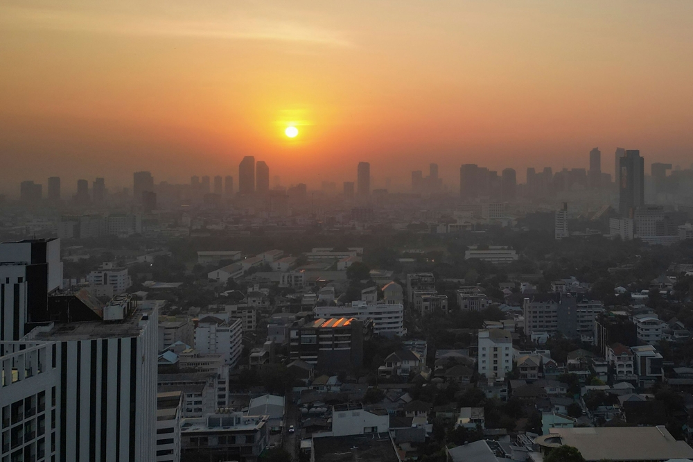 This aerial photo shows sunrise amid high levels of air pollution in Bangkok on January 9, 2024. (Photo by Lillian SUWANRUMPHA / AFP)