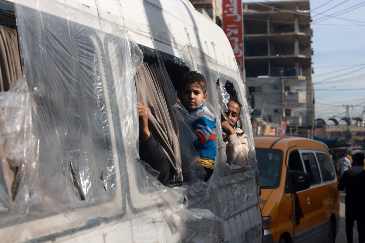 Palestinians look from the windows of a minibus at a market in Rafah refugee camp in the Gaza Strip on January 8, 2024. Photo by AFP