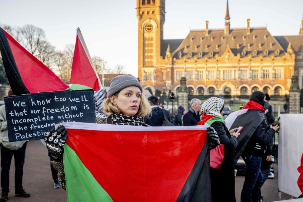 A protestor holds a Palestinian flag during a demonstration simultaneously at the hearing at the International Court of Justice (ICJ) in The Hague, January 11, 2024. Photo by Robin Utrecht / ANP / AFP