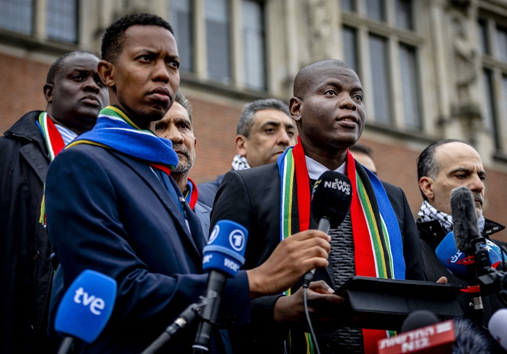 South Africa's Minister of Justice Ronald Lamola (R) delivers remarks to journalists outside the International Court of Justice (ICJ) after the first day of hearing on the genocide case against Israel brought by South Africa, in The Hague on January 11, 2024. (Photo by Remko de Waal / ANP / AFP)