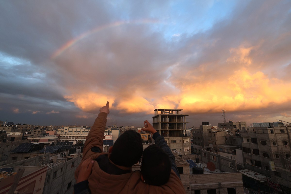 A picture taken from Rafah shows children pointing towards a rainbow over the southern Gaza Strip on January 11, 2024. Photo by AFP