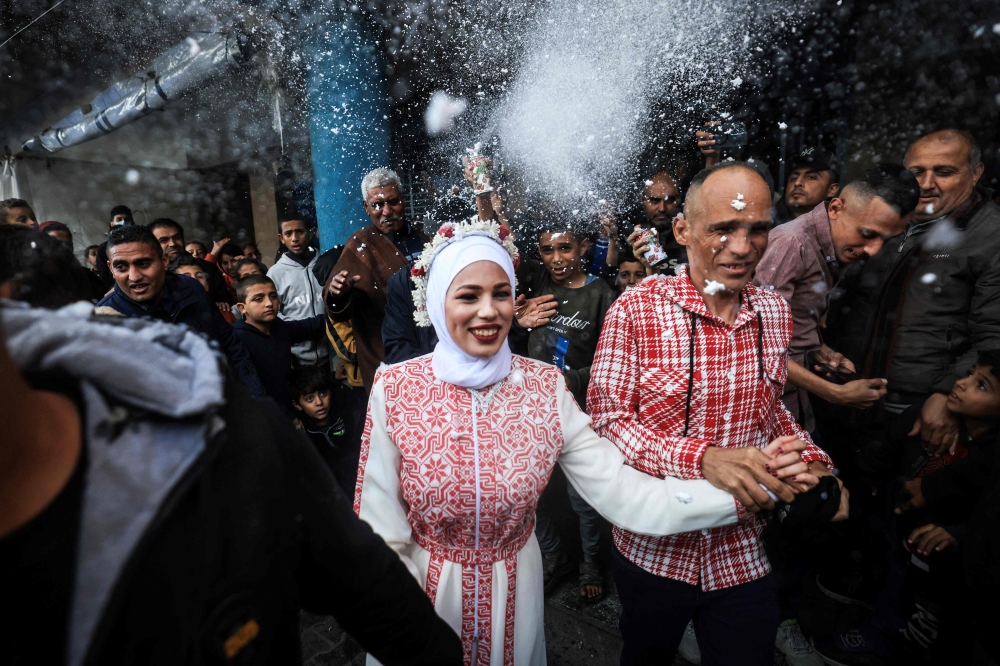 Palestinian bride Afnan Jibril (C) is escorted by her father (C-R) during her wedding at the UNRWA School in the al-Salam neighborhood of Rafah, southern Gaza Strip, on January 12, 2024. (Photo by AFP)