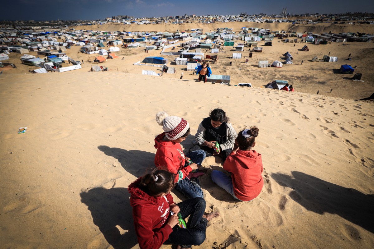 Displaced Palestinian children play on a sand dune above a makeshift camp on the Egyptian border, west of Rafah in the southern Gaza Strip on January 14, 2024. Photo by AFP