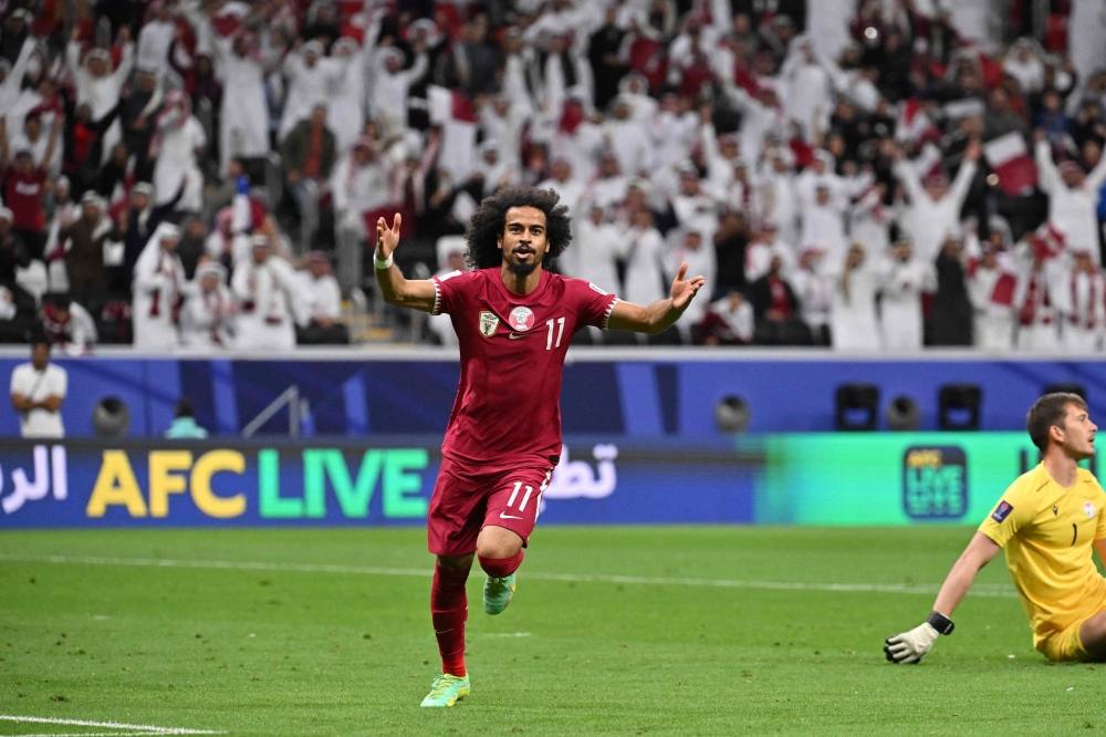 Qatar's forward #11 Akram Afif celebrates after scoring his team's first goal as Tajikistan's goalkeeper #01 Rustam Yatimov reacts during the Qatar 2023 AFC Asian Cup Group A football match between Tajikistan and Qatar at the Al-Bayt Stadium in Al Khor, north of Doha on January 17, 2024. (Photo by HECTOR RETAMAL / AFP)
