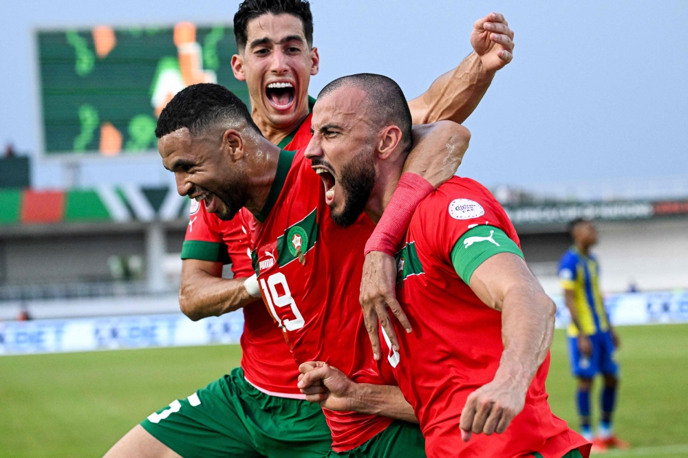 Morocco's defender #6 Romain Saiss (R) celebrates with Morocco's forward #19 Youssef En-Nesyri (C) and Morocco's defender #5 Nayef Aguerd (L) after scoring his team's first goal during the Africa Cup of Nations (CAN) 2024 group F football match between Morocco and Tanzania at Stade Laurent Pokou in San Pedro on January 17, 2024. (Photo by SIA KAMBOU / AFP)