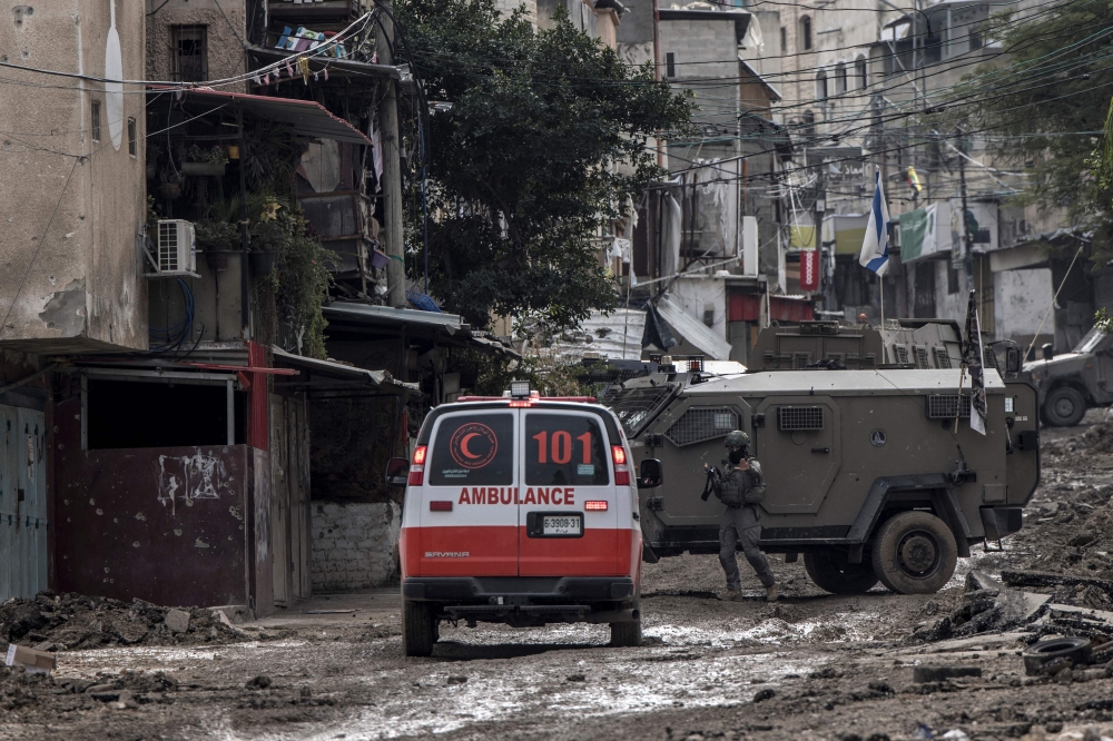 An Israeli soldier gestures towards a Palestinian Red Crescent ambulance at the entrance of the Tulkarem refugee camp in Tulkarem, in the occupied West Bank, on January 17, 2024. (Photo by Marco Longari / AFP) 