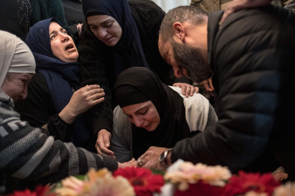 The mother (C) of 17-year-old Palestinian Tawfeek Ajaq mourns over his body ahead of his funeral procession on January 20, 2024. (Photo by Marco Longari / AFP)