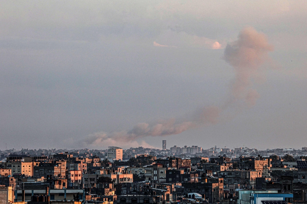 A picture taken from Rafah in the southern Gaza Strip shows smoke rising over buildings in Khan Yunis following Israeli bombardment on February 3, 2024. (Photo by Said Khatib / AFP)