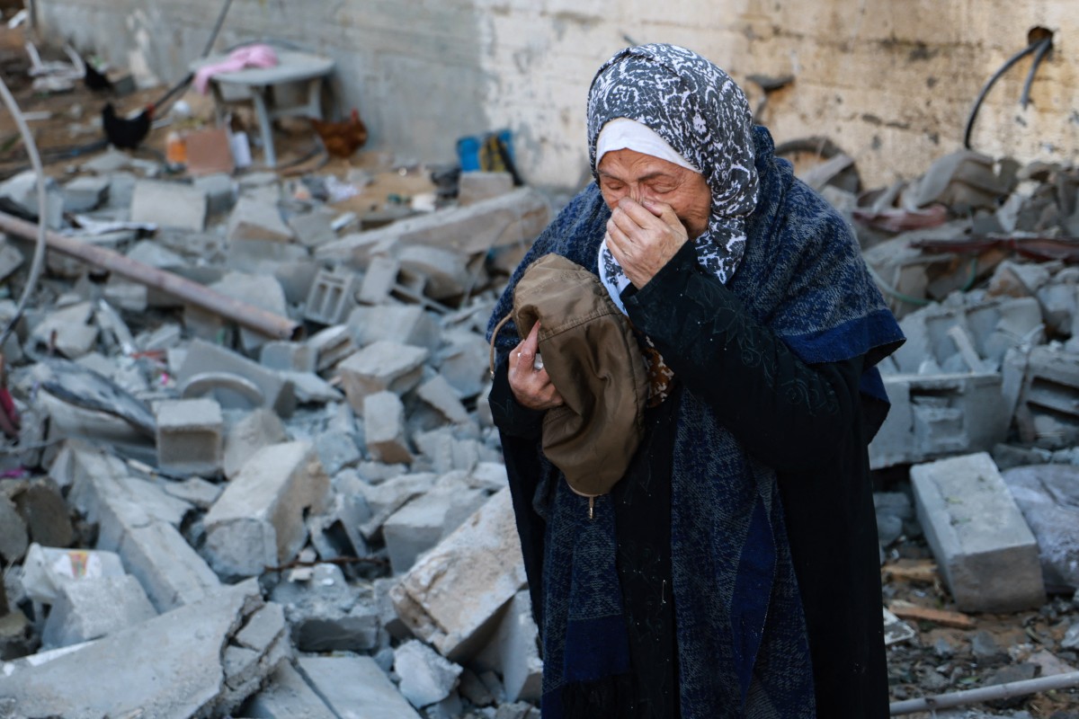 A woman reacts upon finding clothing items of a killed relative among rubble of a destroyed house, following Israeli bombardment in Rafah in the southern Gaza Strip on February 3, 2024. Photo by Mohammed ABED / AFP