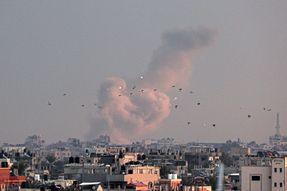 A picture taken from Rafah in the southern Gaza Strip shows smoke rising over buildings in Khan Yunis following Israeli bombardment on February 5, 2024. (Photo by Said Khatib / AFP)