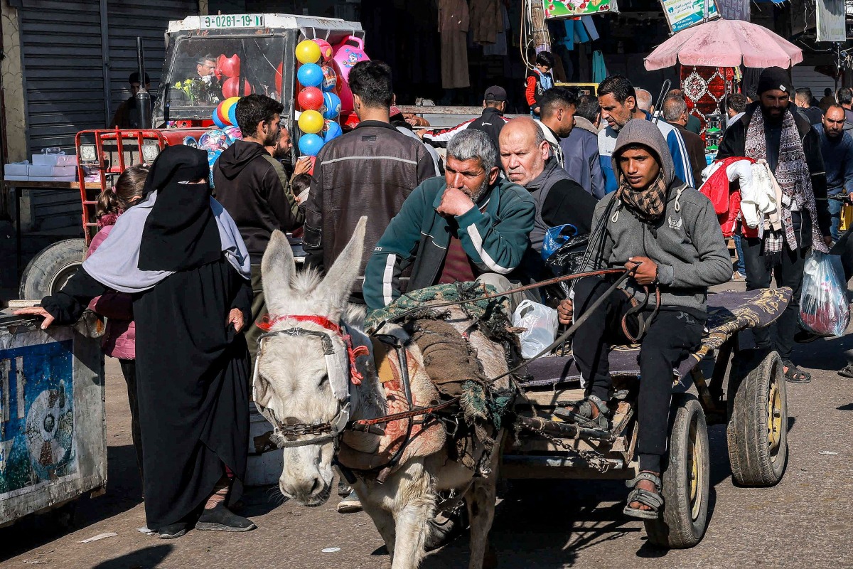 A youth drives a donkey-drawn cart along a crowded main street in Rafah in the southern Gaza Strip yesterday.  (AFP)