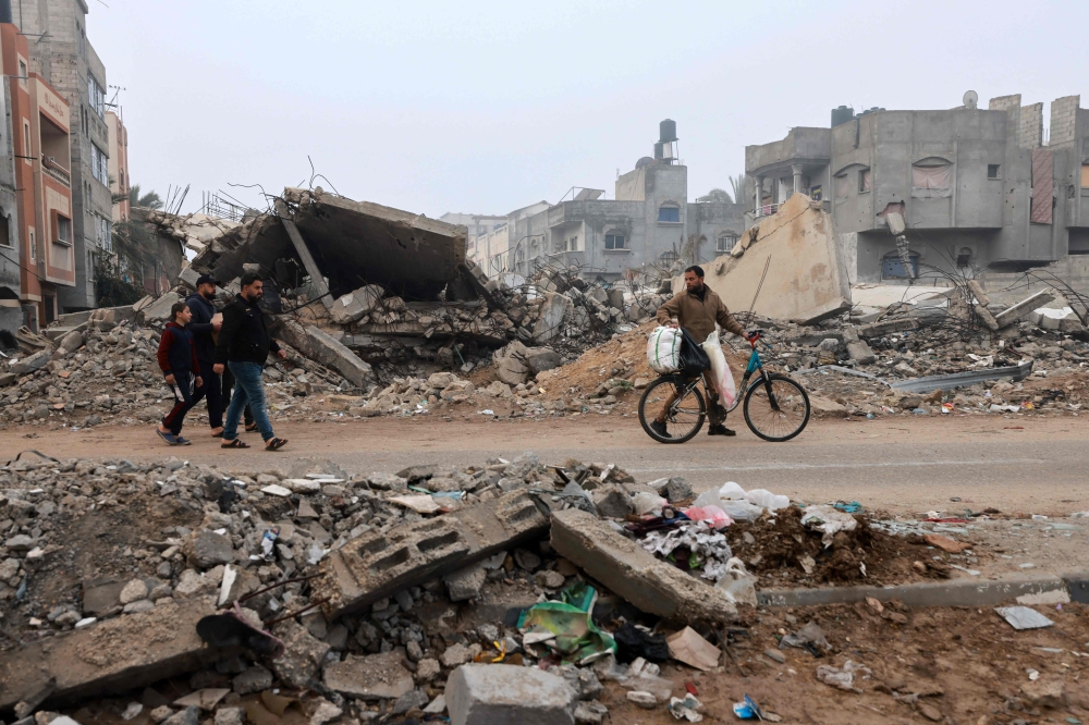 Men walk along a street ravaged by Israeli bombing in Rafah in the southern Gaza Strip on February 9, 2024. (Photo by Mohammed ABED / AFP)