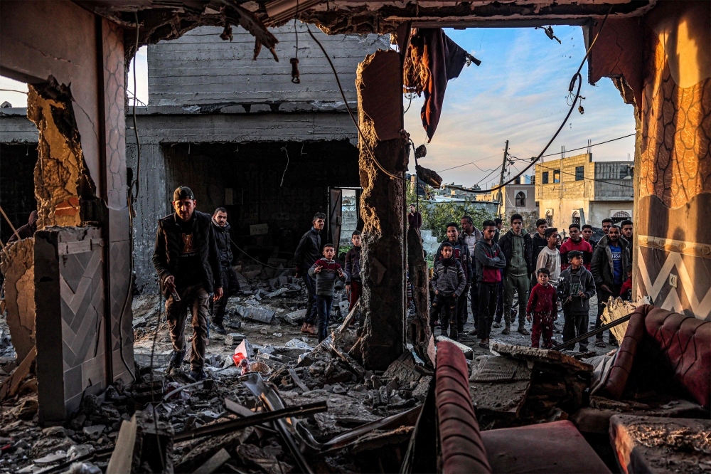 People inspect debris and rubble in a building heavily damaged by Israeli bombardment, in Rafah in the southern Gaza Strip on February 11, 2024. Photo by SAID KHATIB / AFP