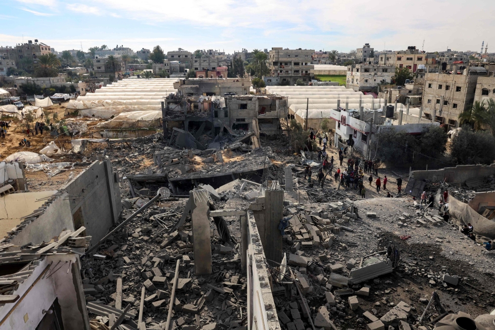 Palestinians inspect the damage amid the rubble of a building bombed in Rafah, on the southern Gaza Strip on February 12, 2024. (Photo by Said Khatib / AFP)