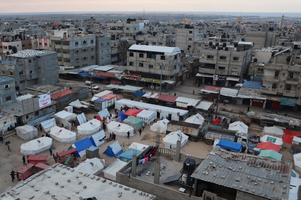 Displaced Palestinians stand outside their tents in Rafah in the southern Gaza Strip on February 14, 2024. Photo by SAID KHATIB / AFP