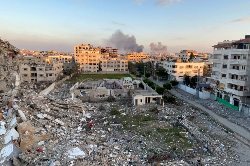 A picture taken in Gaza City shows debris from destroyed buildings and smoke billowing in the background during Israeli bombardment on February 20, 2024. (Photo by AFP)