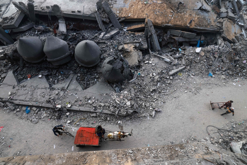 A donkey-pulled car passes in front of the Al-Faruq mosque, levelled by Israeli bombardment in Rafah in the southern Gaza Strip on a foggy day on February 25, 2024, amid continuing battles between Israel and the Palestinian group Hamas. (Photo by MOHAMMED ABED / AFP)
