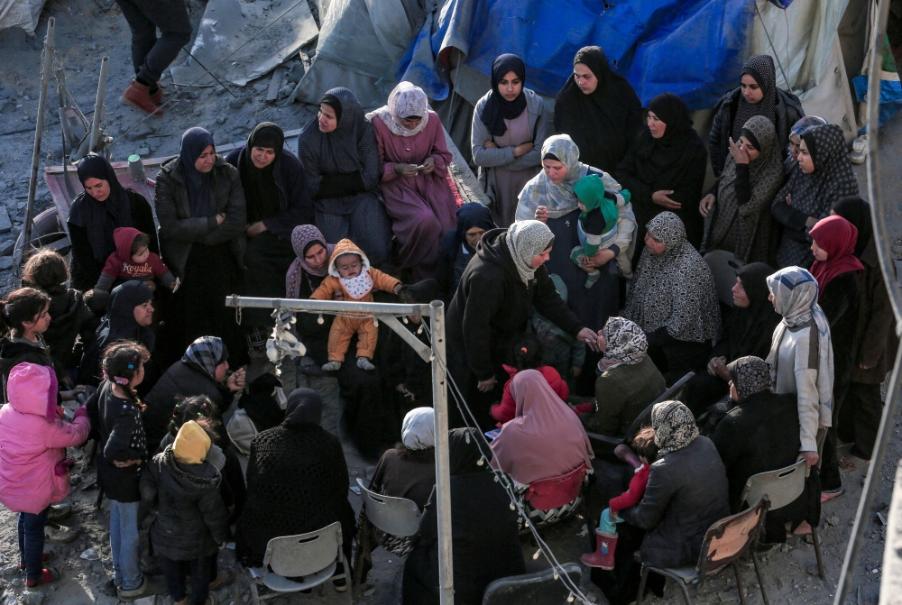 Palestinians sit amid tents and makeshift shelters that were destroyed in Israeli strikes in Deir El-Balah in central Gaza on March 2, 2024, as battles continue between Israel and the militant group Hamas. (Photo by AFP)
