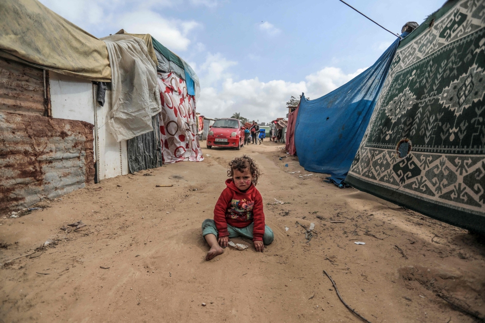 A child plays in a makeshift camp for displaced Palestinians in Deir al-Balah in central Gaza on March 3, 2024. Photo by AFP