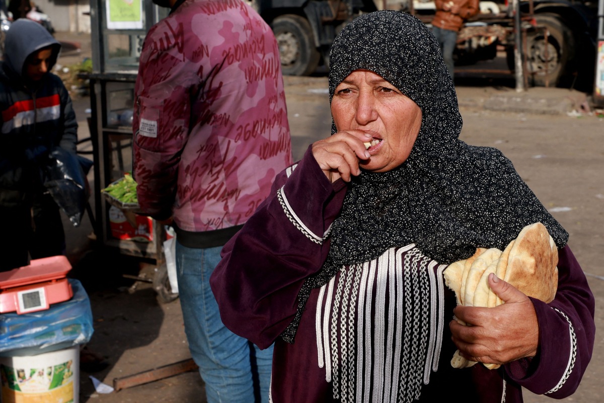 A Palestinian woman eats bread in Rafah in the southern gaza Strip on March 4, 2024 (Photo by AFP)